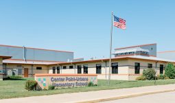 Exterior of a school building with an American flag and a sign that says 