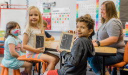 Elementary school students practice writing the letter P on chalkboards