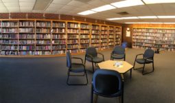 Panoramic view of the middle school library with shelves along the wall and a table with chairs in the foreground